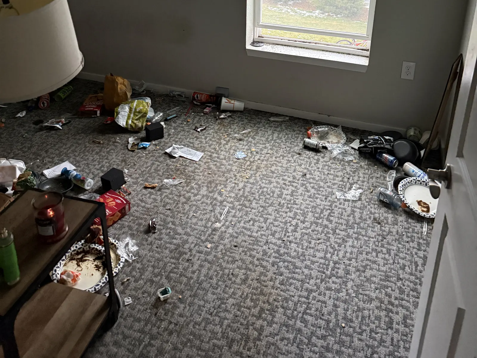 Loose household debris across a bedroom floor before a property cleanout